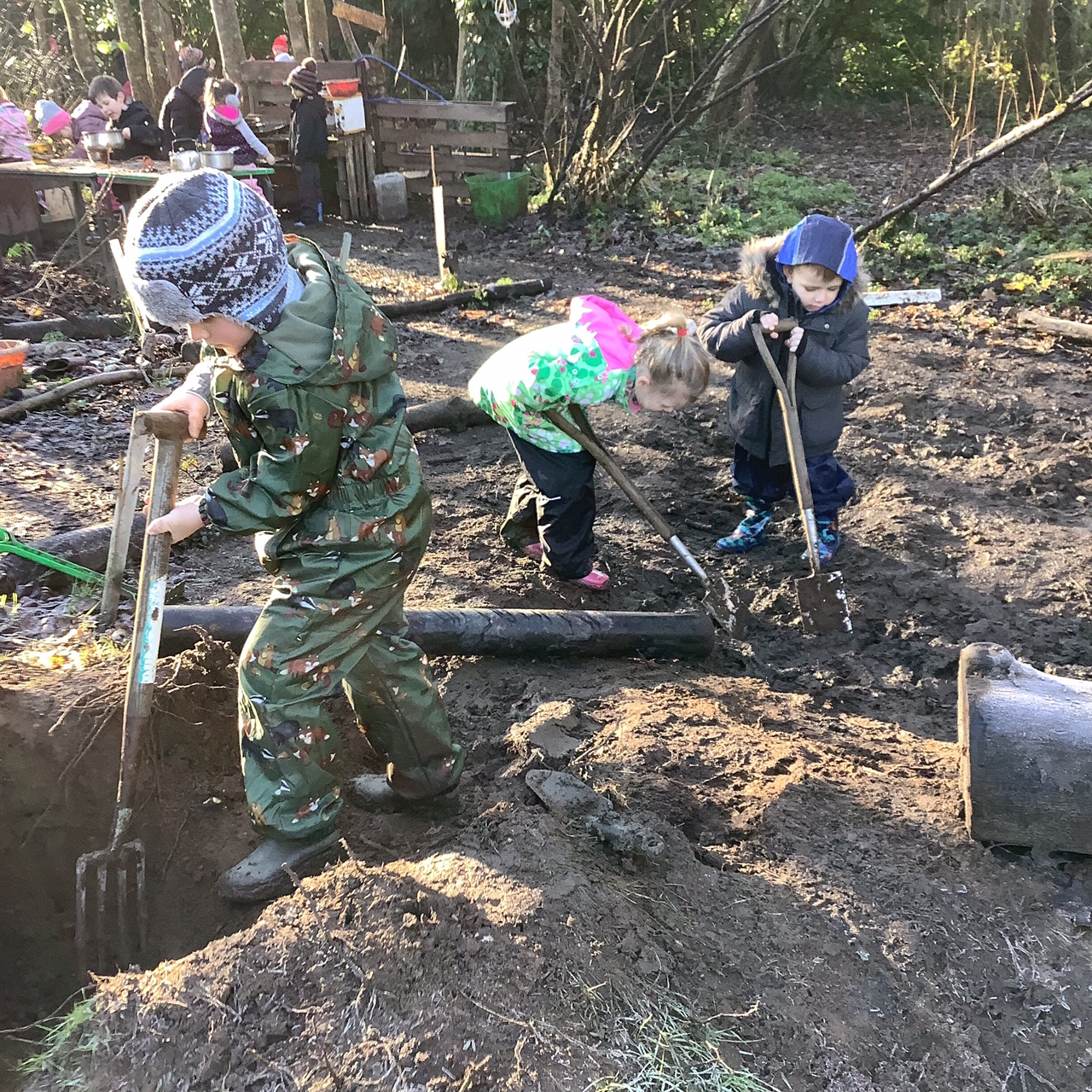 Children digging in mud with spades and forks