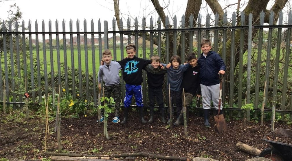 Children stood around the trees they just planted