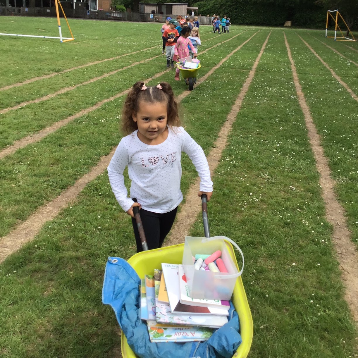 Children pushing wheelbarrows full of equipment