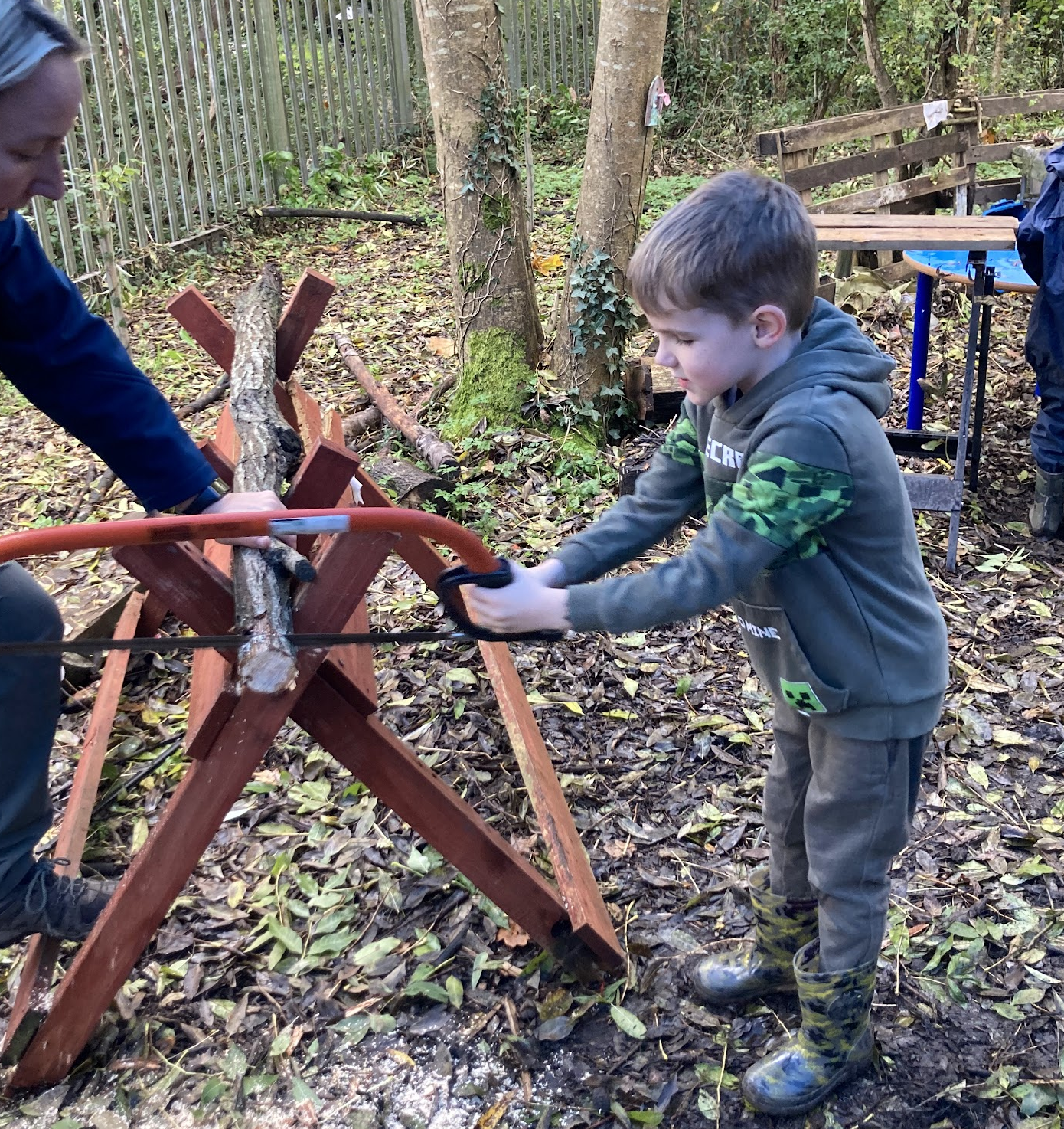 A child being shown how to use the bow saw